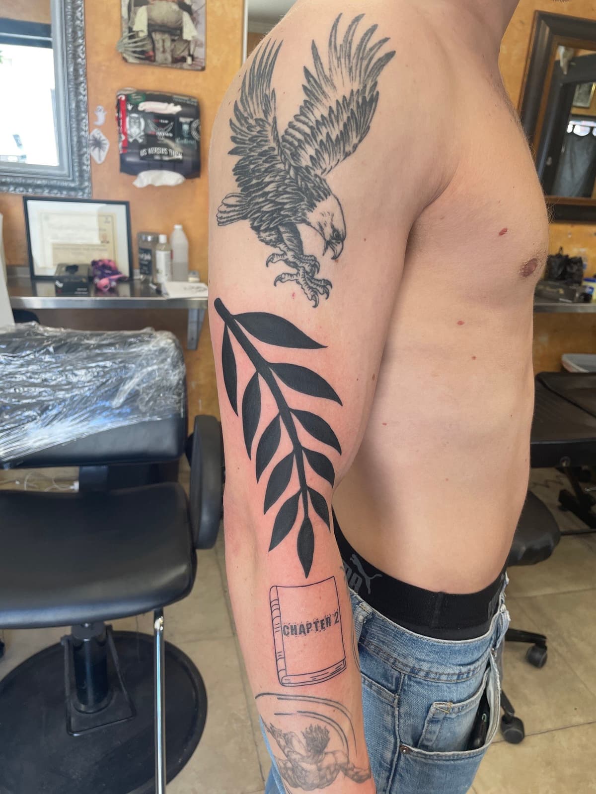 Blackwork tattoo bold fern leaf branch on inner bicep in Los Angeles