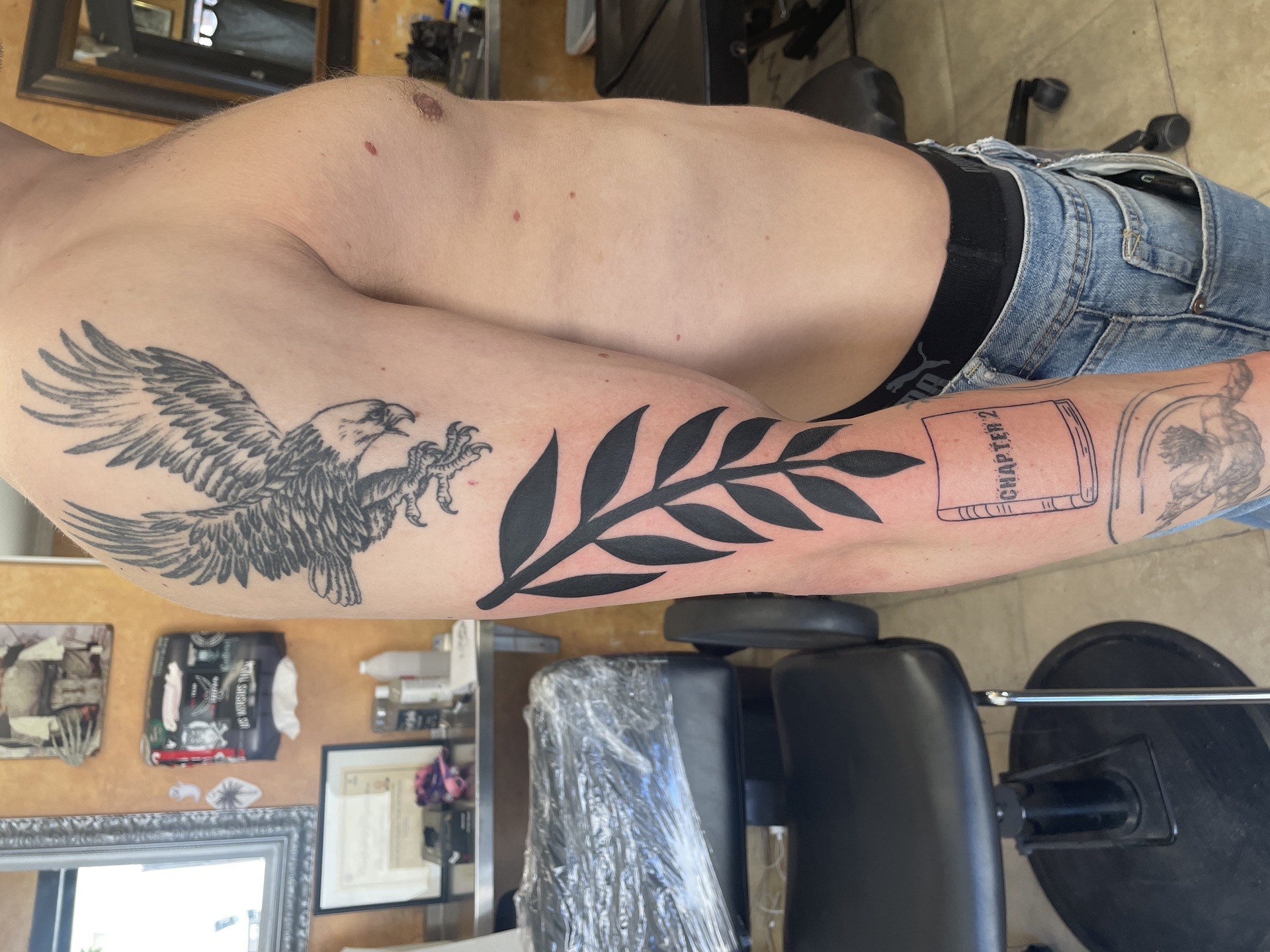 Blackwork tattoo bold fern leaf branch on inner bicep in Los Angeles