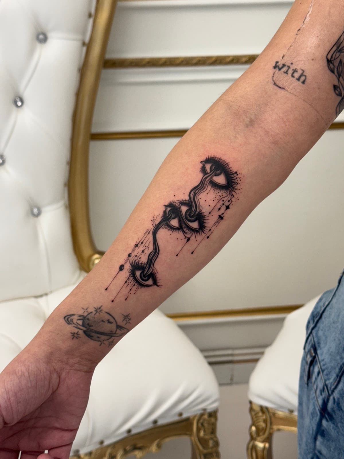 Blackwork tattoo surreal eyes with snakes and celestial planet on forearm in Los Angeles