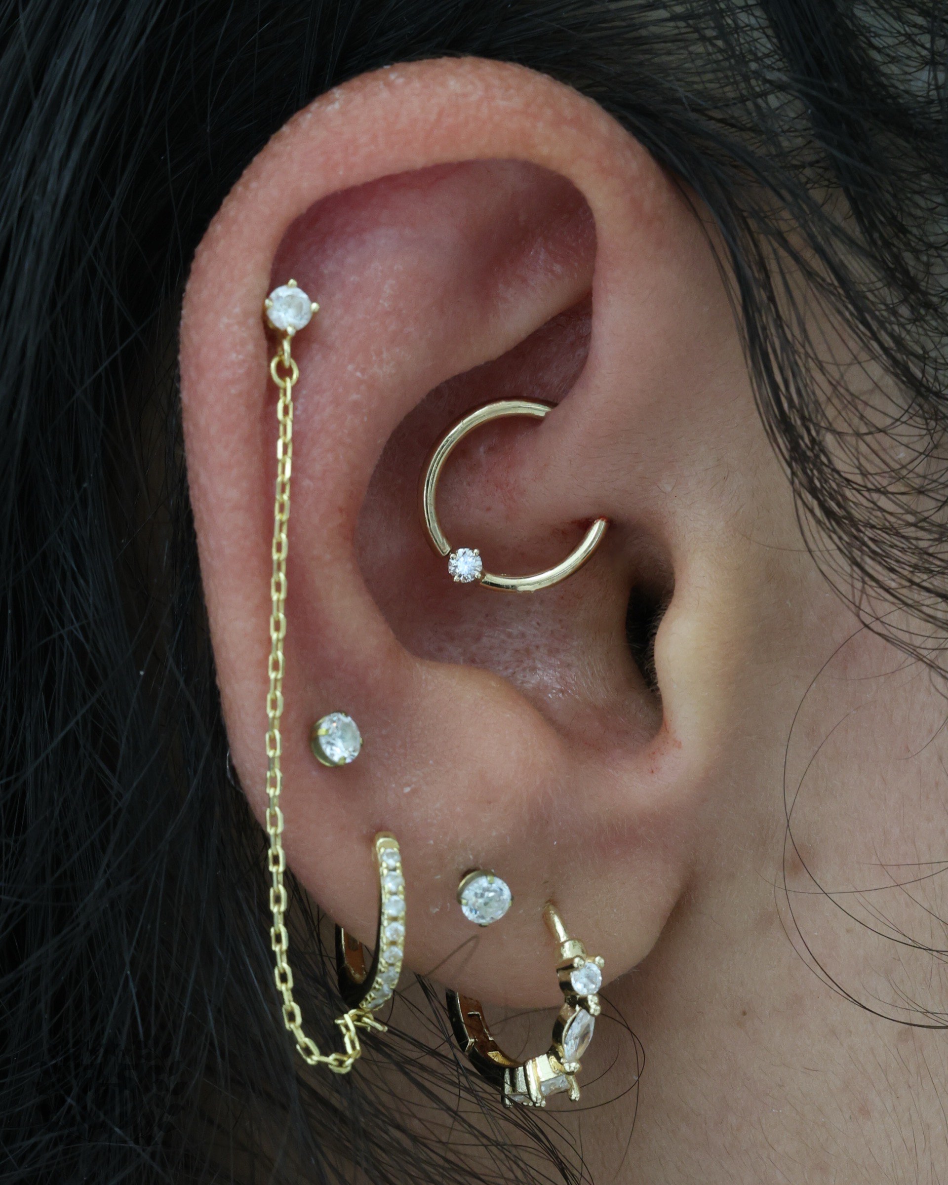 Gold hoop daith piercing with CZ gemstone accent and curated ear jewelry at Apollo Studio Los Angeles
