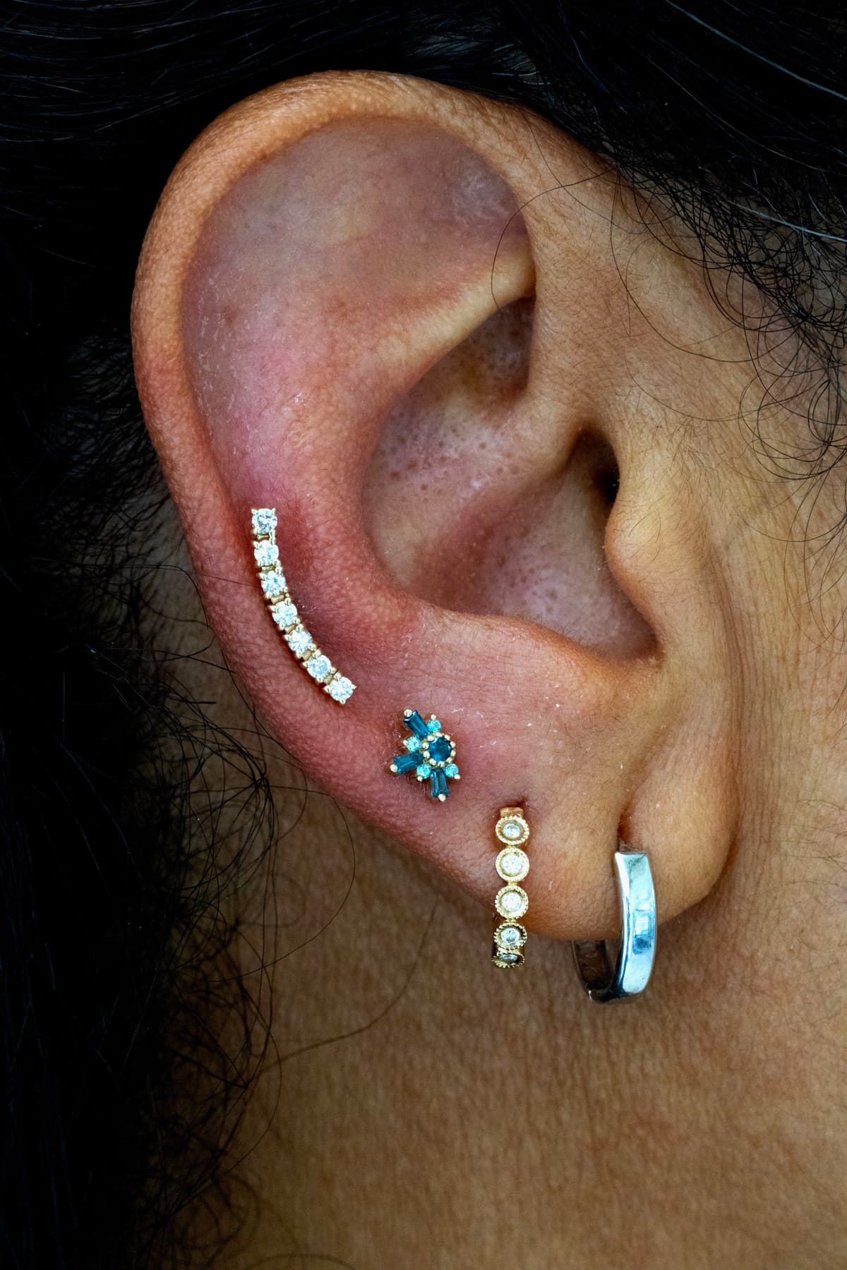 Gold CZ crawler ear cartilage piercing with blue flower lobe stud at Apollo Studio