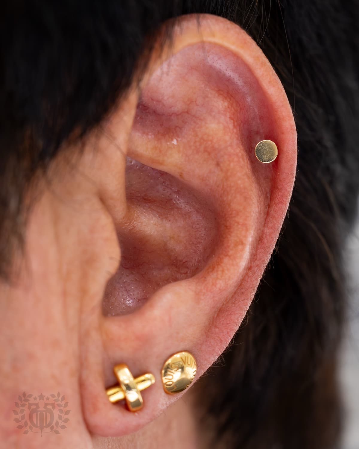 Gold flat disc cartilage stud with BVLA gold cross lobe earrings at Apollo Studio