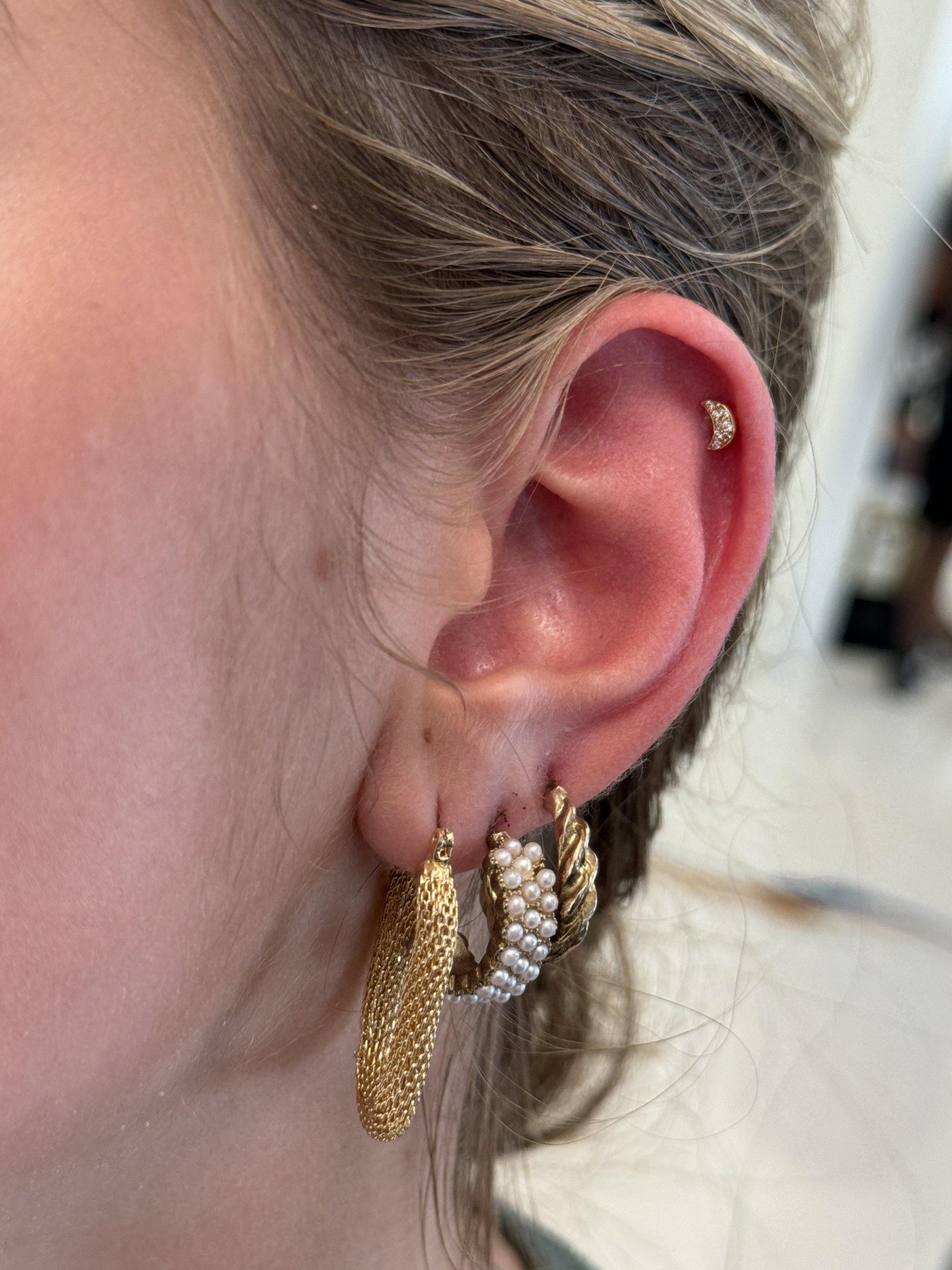 Gold CZ crescent moon cartilage stud with pearl and rope lobe hoops at Apollo Tattoo and Piercing