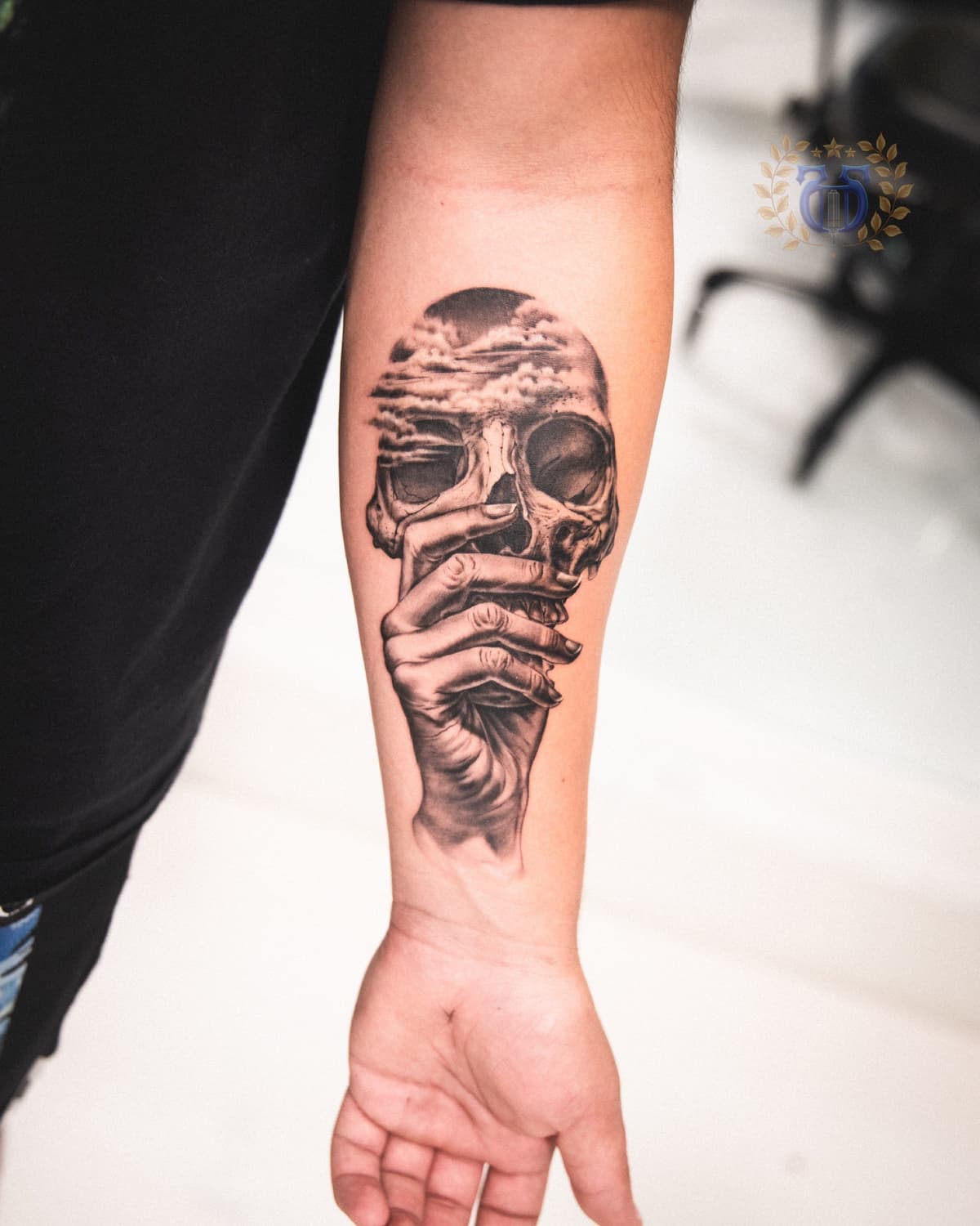 Surreal skull held by hand with clouds realism tattoo on forearm in Los Angeles