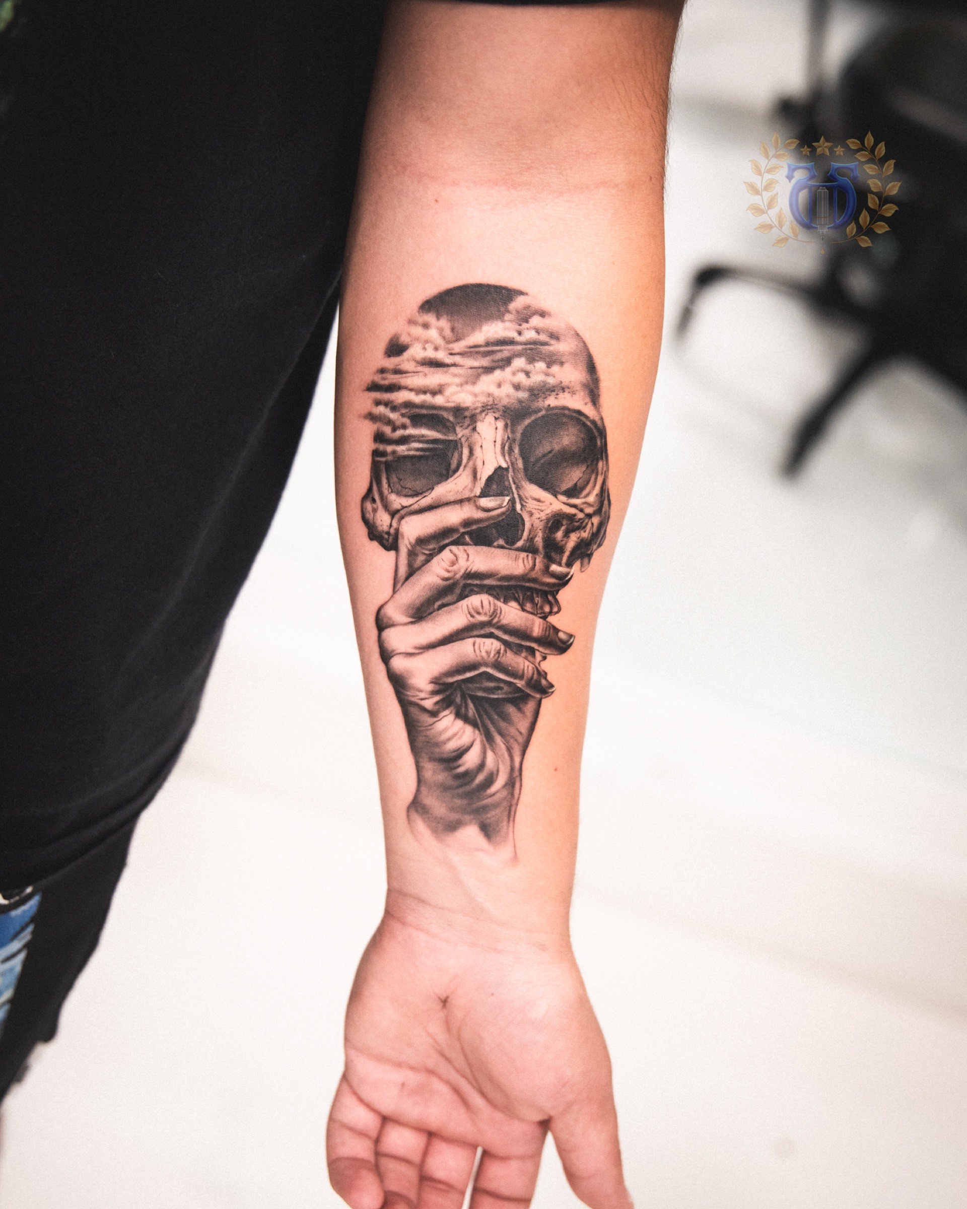 Surreal skull held by hand with clouds realism tattoo on forearm in Los Angeles