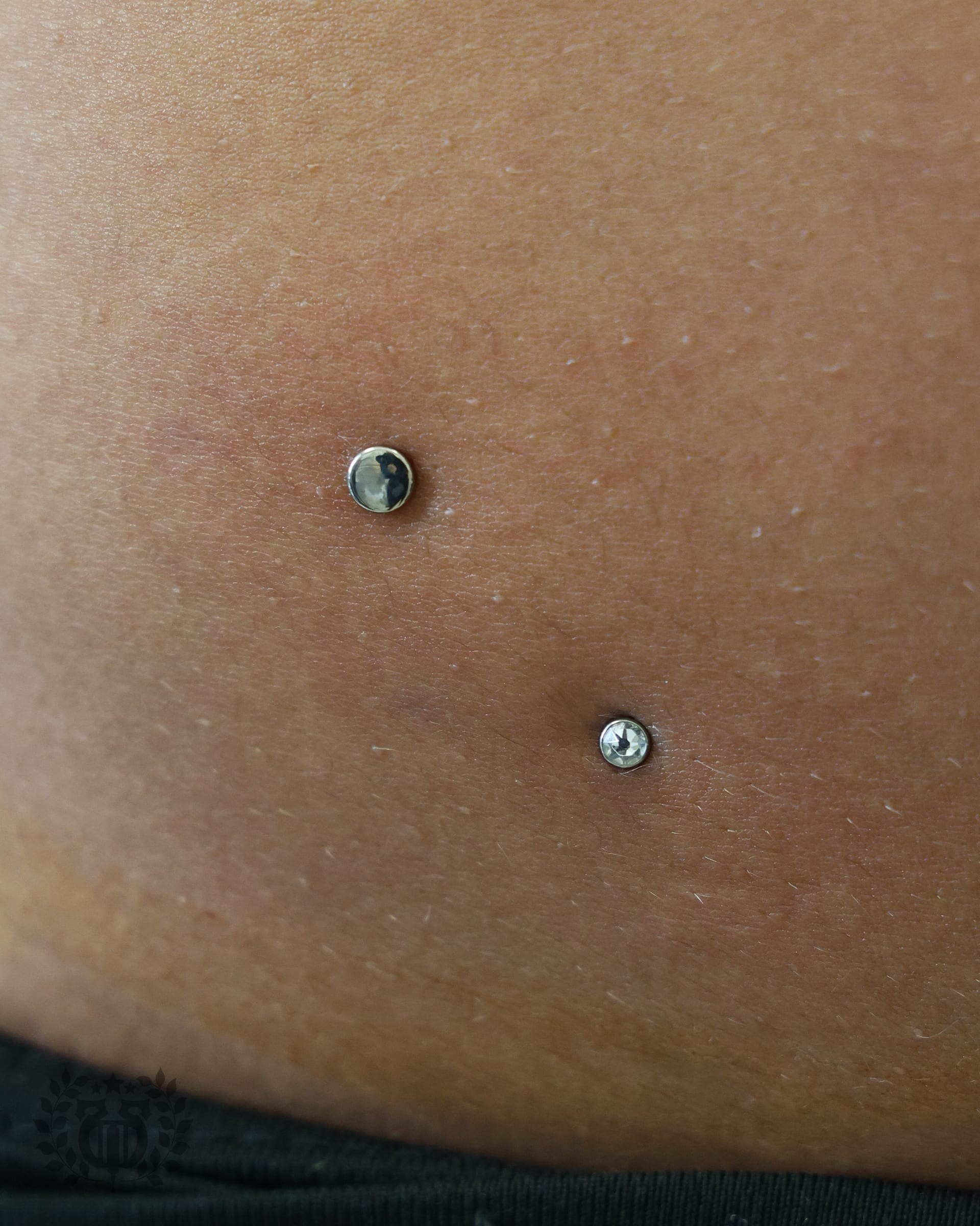 Double hip dermal anchor piercings with CZ gemstone tops at Apollo Studio Los Angeles