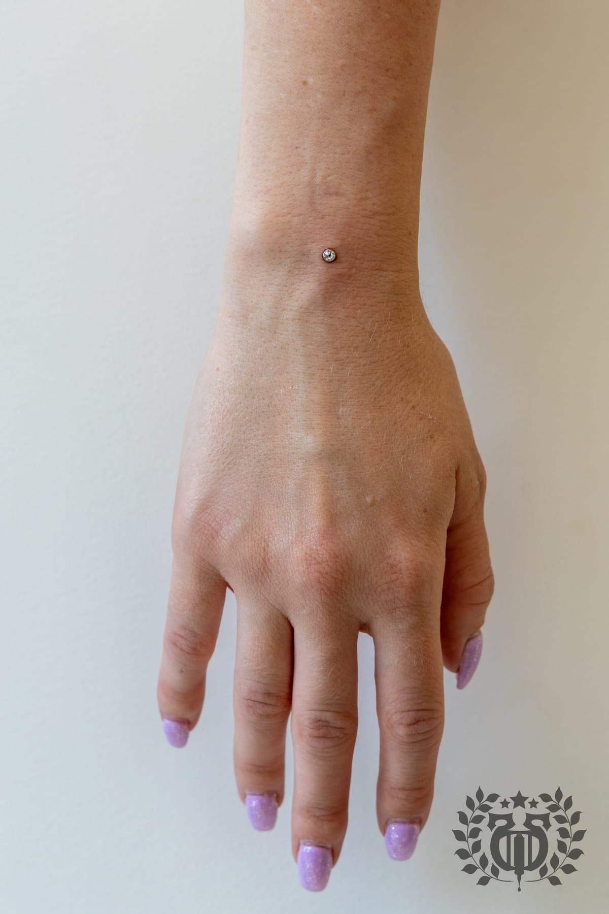 Wrist dermal anchor piercing with CZ top on back of hand at Apollo Studio Los Angeles