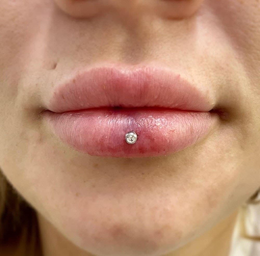 Center lower lip piercing with gold CZ bezel stud close-up at Apollo Studio Los Angeles