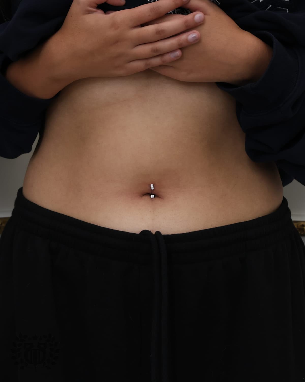 Belly button piercing with prong-set CZ curved barbell on client at Apollo Tattoo and Piercing