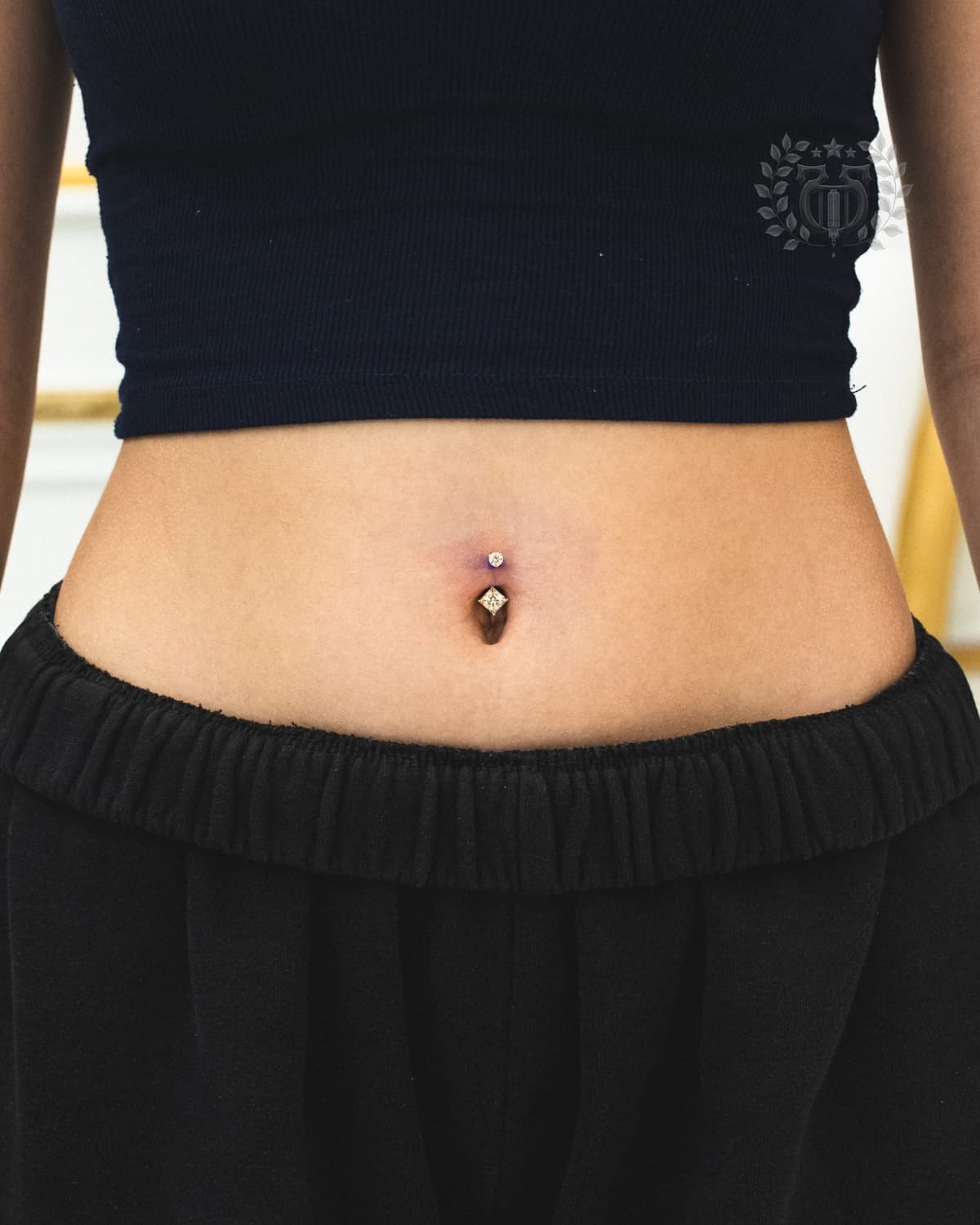 Belly button piercing with double CZ prong-set curved barbell at Apollo Studio LA