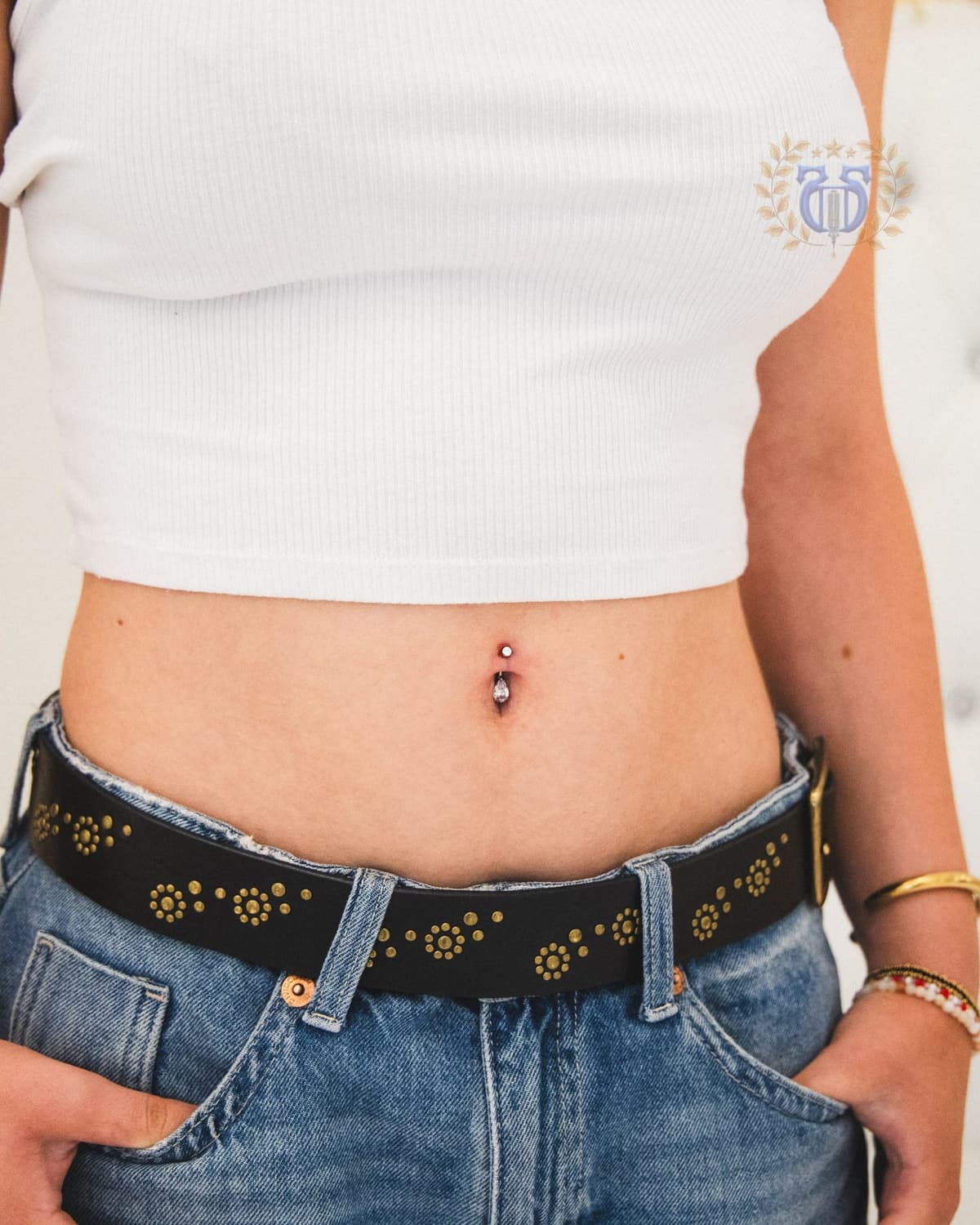 Close-up navel piercing with double CZ bar curved barbell implant-grade titanium at Apollo Studio