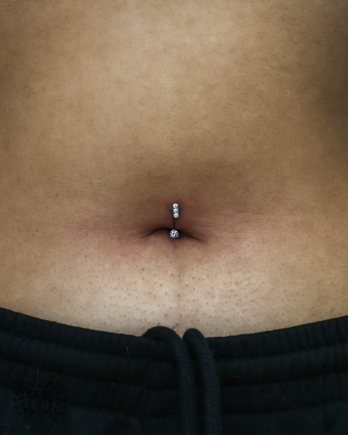 Belly button piercing with halo CZ flower cluster curved barbell at Apollo Studio Los Angeles