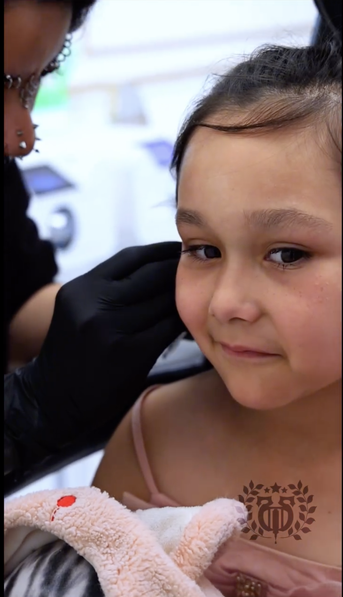 A young child receives a safe, gentle piercing at Apollo Studio while holding her favorite plush toy for comfort.